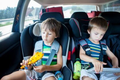 Cómo viajar con niños largos trayectos en coche - dos ninyos jugando en el coche