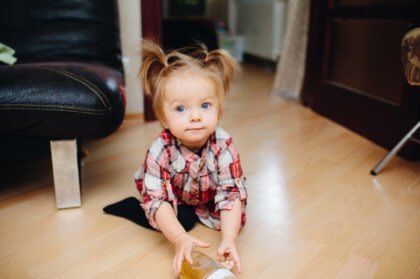 niña pequeña en el suelo cogiendo su biberón