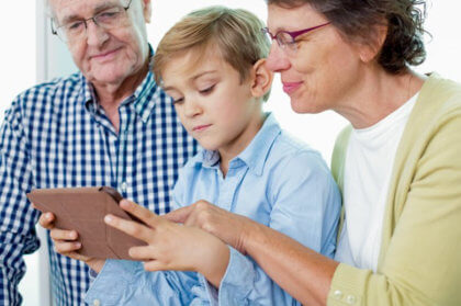 Domótica para personas mayores-Niño enseñando a mayores en tablet