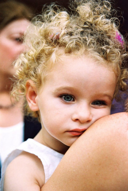 niña con rizos con mirada pensative en brazos de su madre