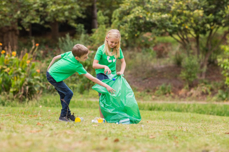 dos niños recogiendo basura en un parque para reciclar