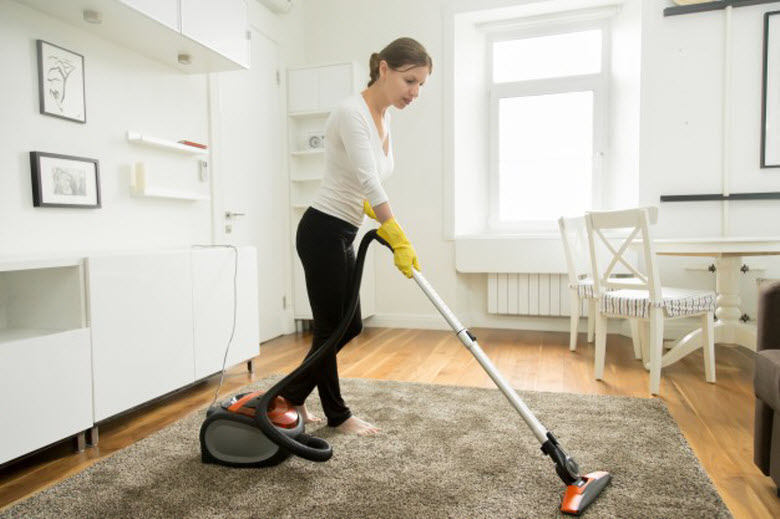 empleada de hogar aspirando la alfombra en el salón