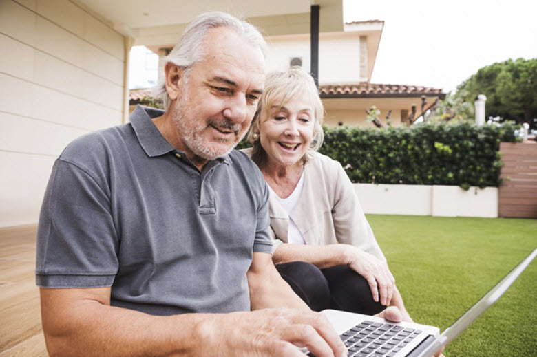 pareja de personas mayores mirando un PC portátil