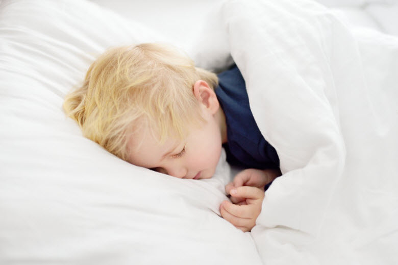 niño durmiendo de lado en cama blanca