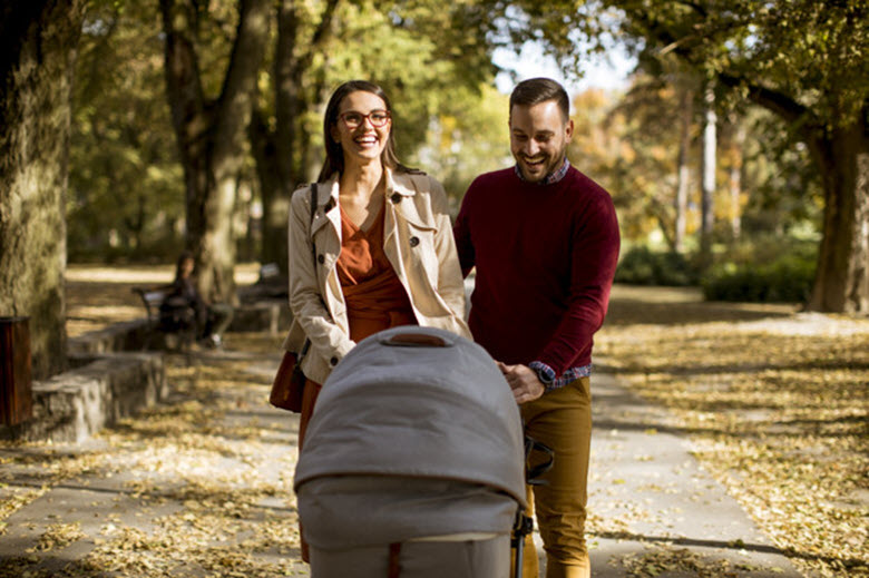 Padres felices paseando su bebé por el parque