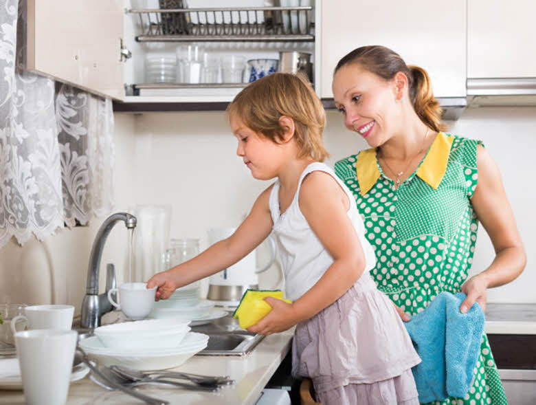 empleada de casa lavando los platos con niña