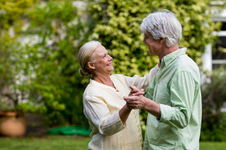 pareja de personas mayores bailando en el jardín